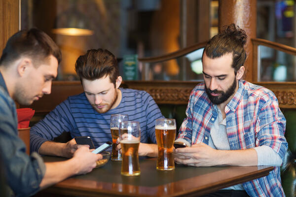 Bilde av menn som drikker øl og er opptatt av mobilen