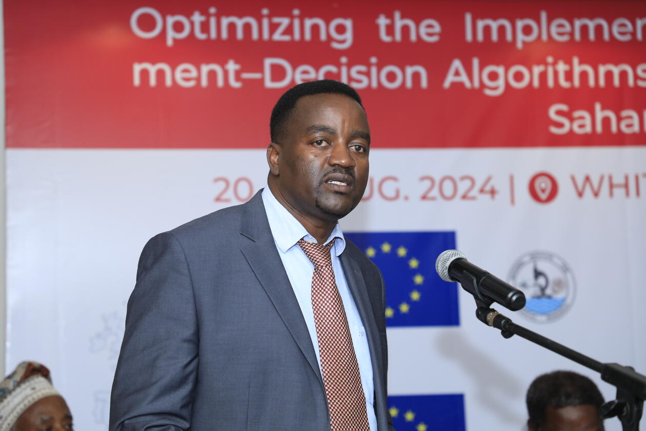 African man giving a speach in front of a project poster