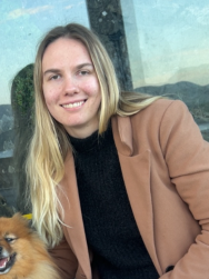 Anita Lid smiler mot kamera, har en hund ved siden av seg