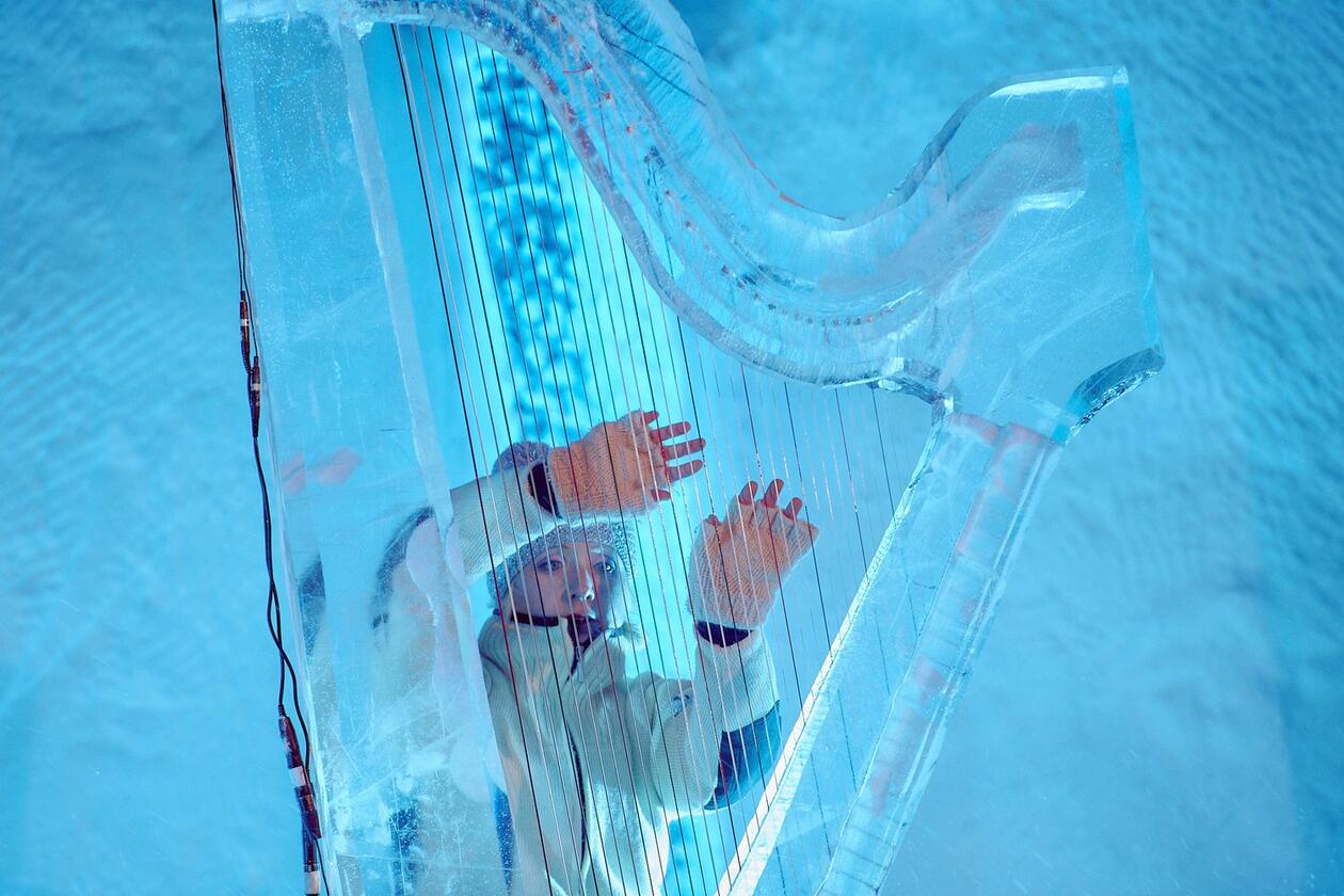 Kvinne spiller på harpe laget av is.