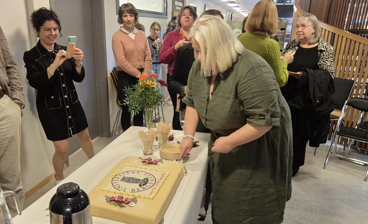 Bilde av Marita Kristiansen som skjærer opp det første kakestykket.