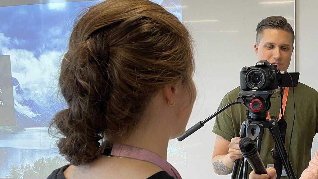 Kommunikasjonsrådgiver og fotograf i arbeid med å intervjue en person