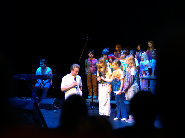 Møhlenpris skolekor på scenen, dirigenten i samtale med tre kormedlemmer