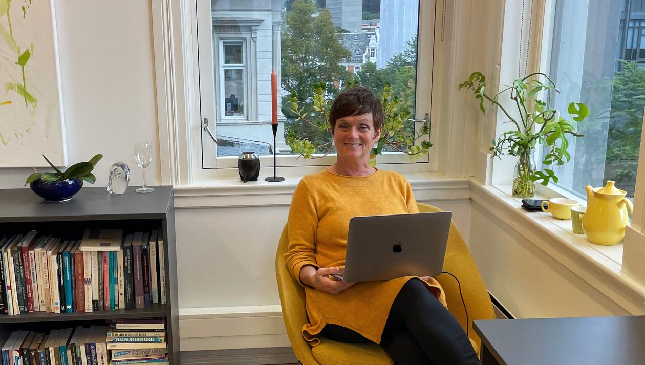 Kvinne med gule klær sitter på kontor på UiB