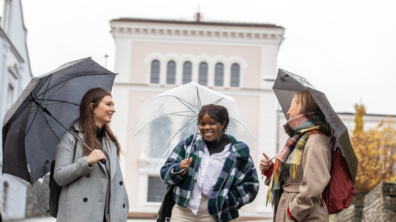 Three happy students with umbrella