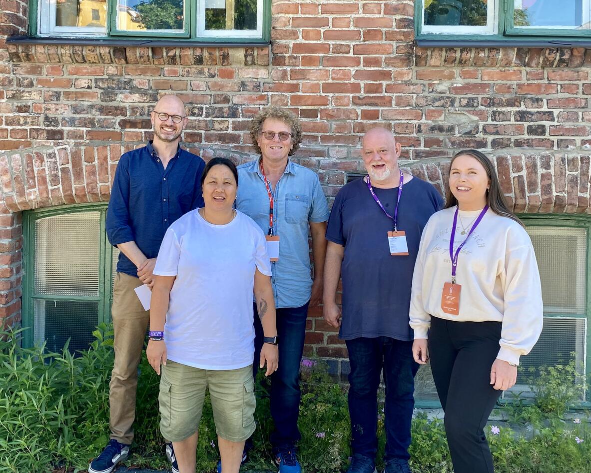 Fem personer står ved siden av hverandre og smiler til kamera.