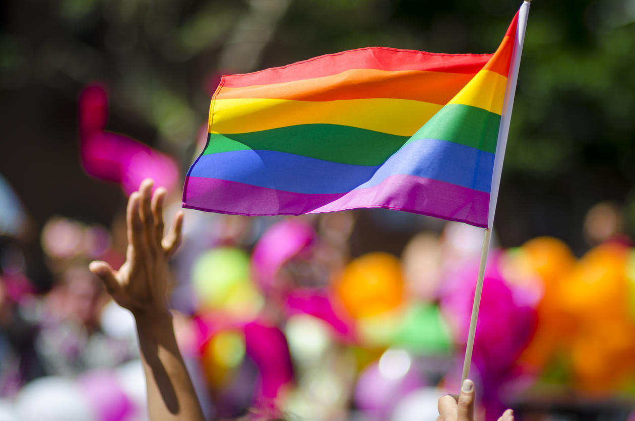 Prideflagg vaier ved siden av en utstrekt arm