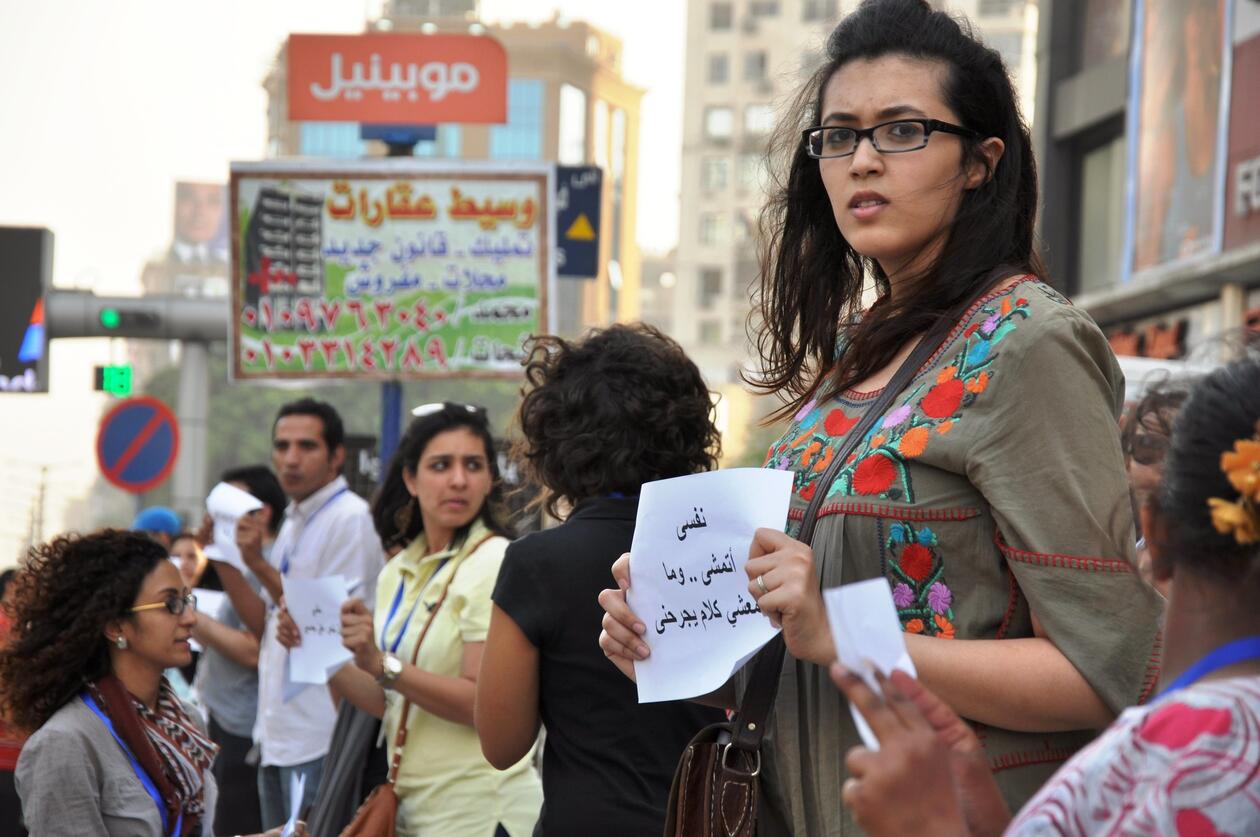 Egyptian woman in a crowd of protesters held up a poster in Arabic
