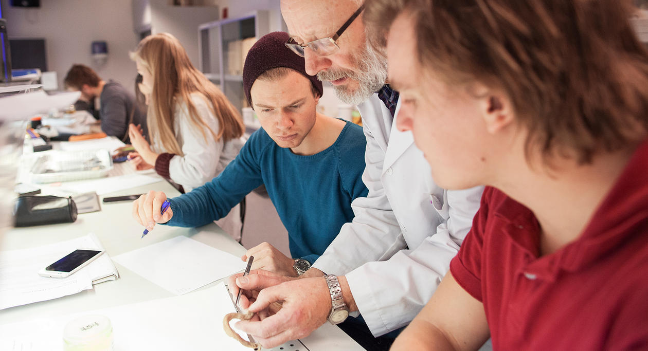 Photo showing teacher instructing a small group of students at workbench