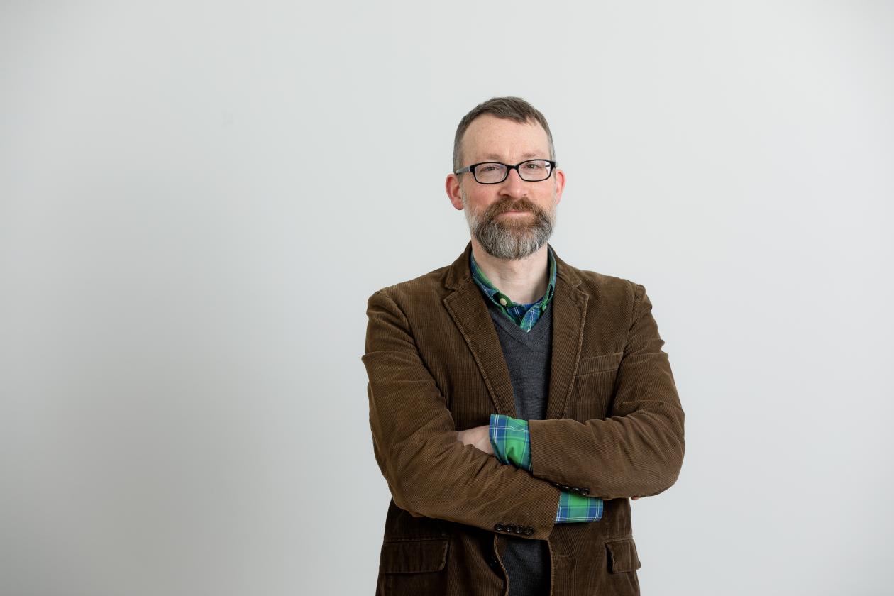 Bildet viser forskeren. En mann med briller og brun blazer. 