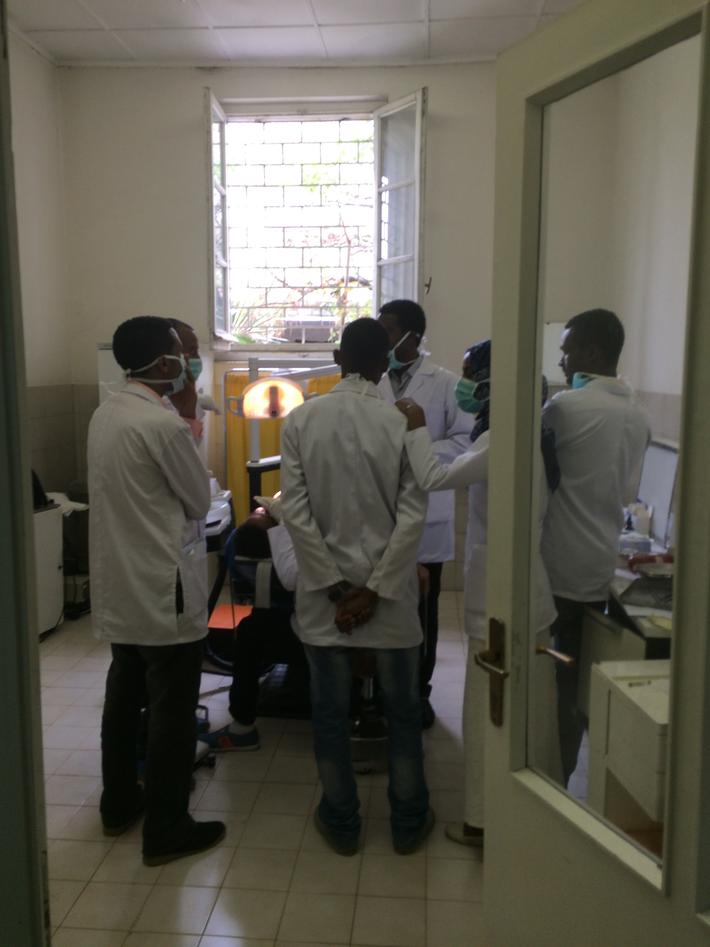 Bilde inne fra School of Dentistry i Addis Ababa, viser flere studenter i samtale rundt en tannlegestol