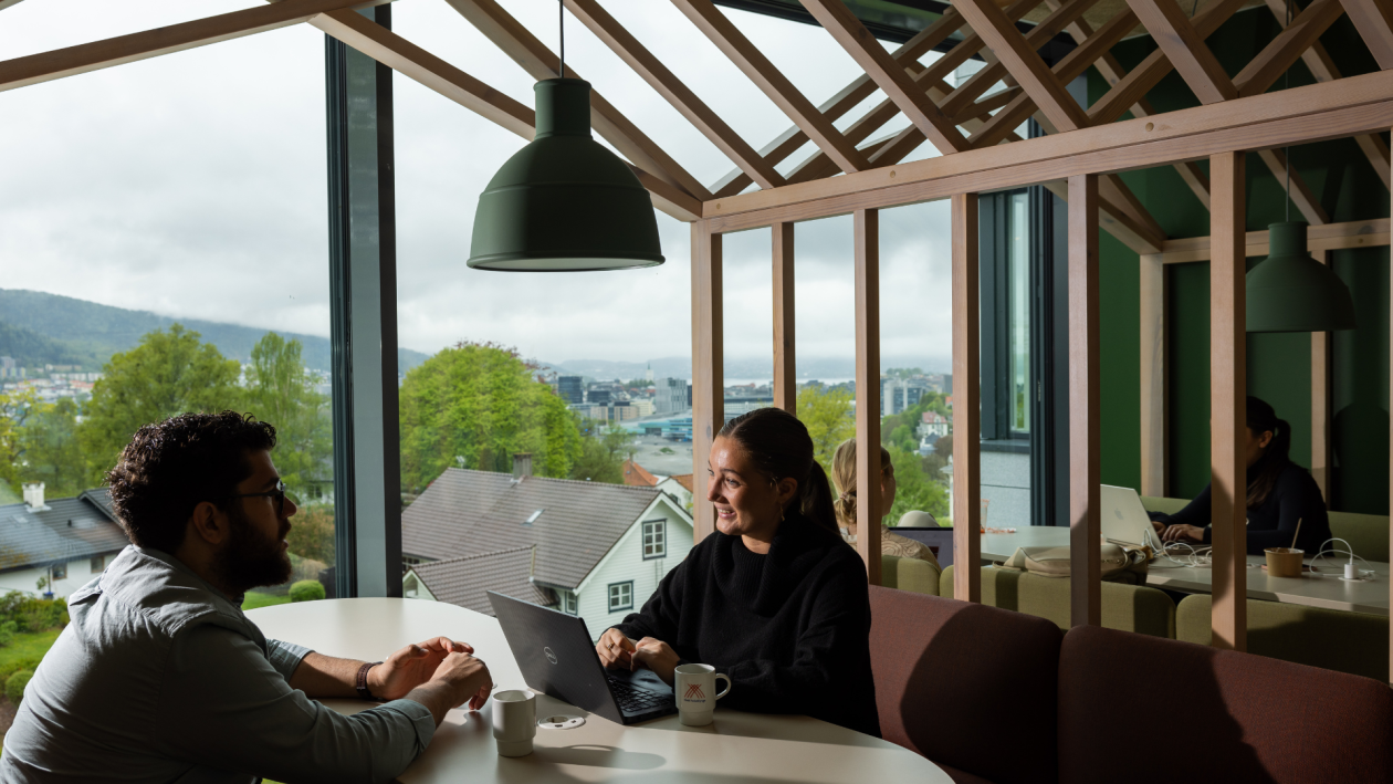 To studenter på sitter ved et bord på campus Bergen