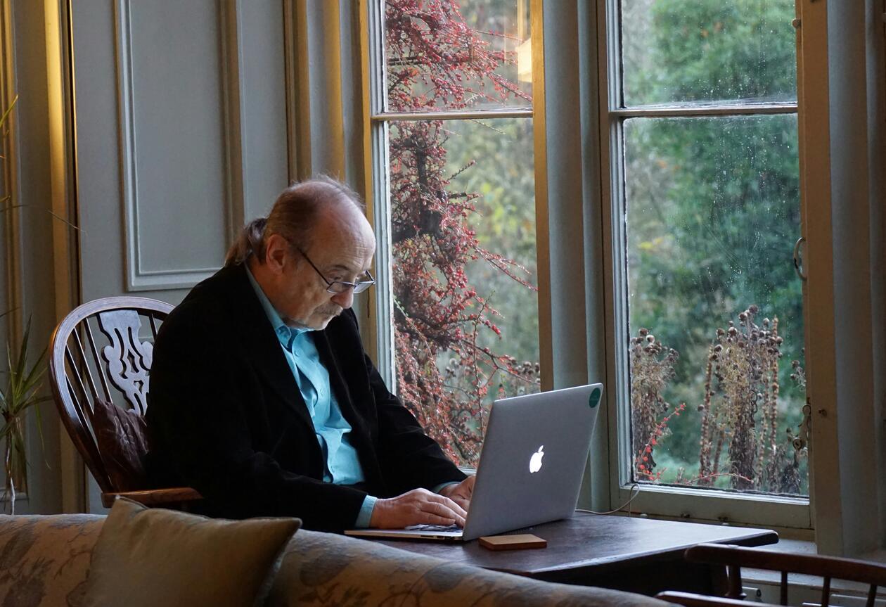 elderly man sits by laptop