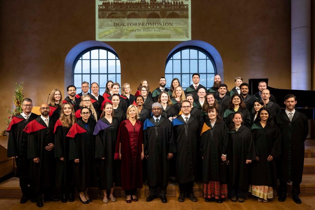 Alle de nye doktores står oppstilt på scenen sammen med fungerende rektor