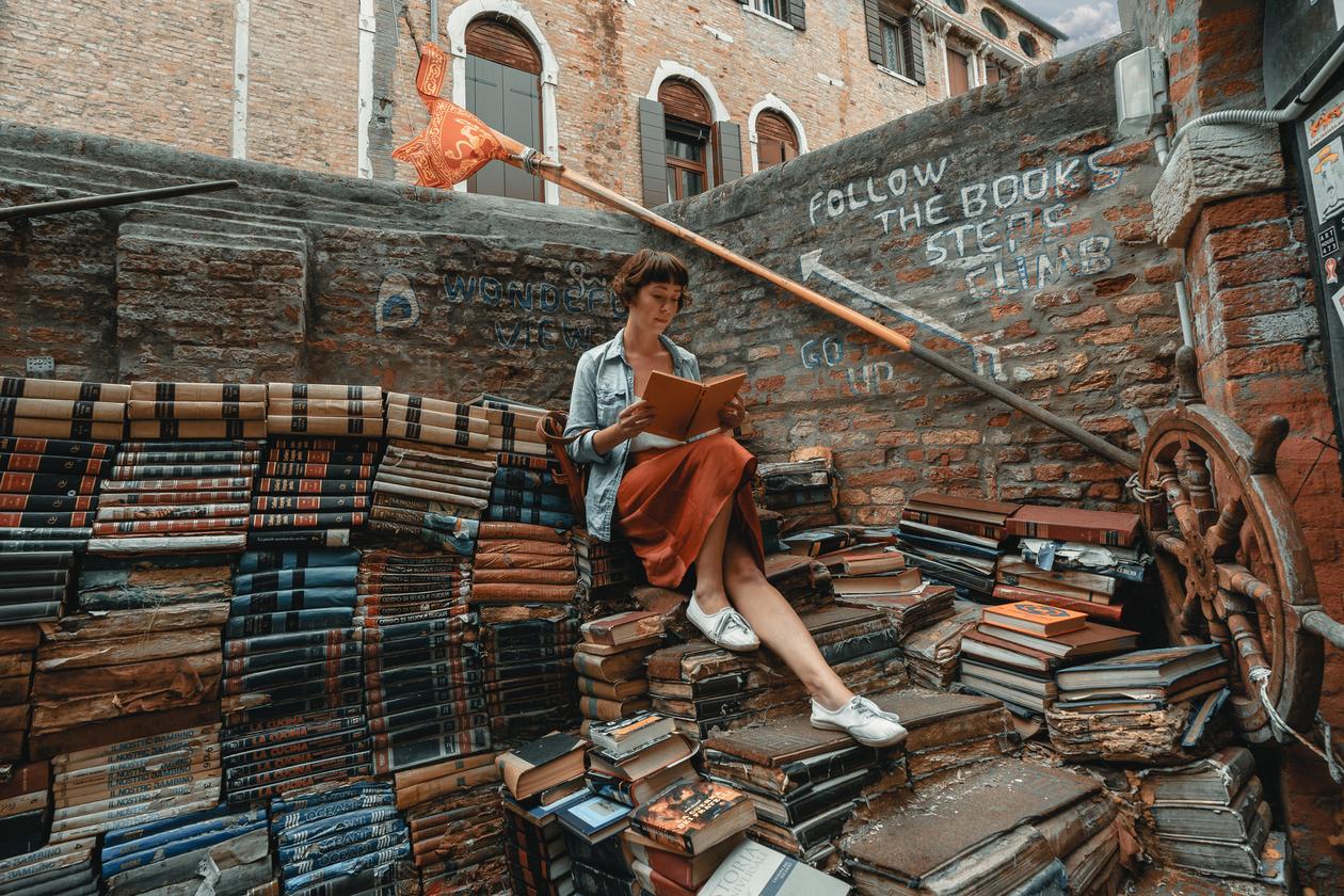 Woman sitting on a books and reading a book