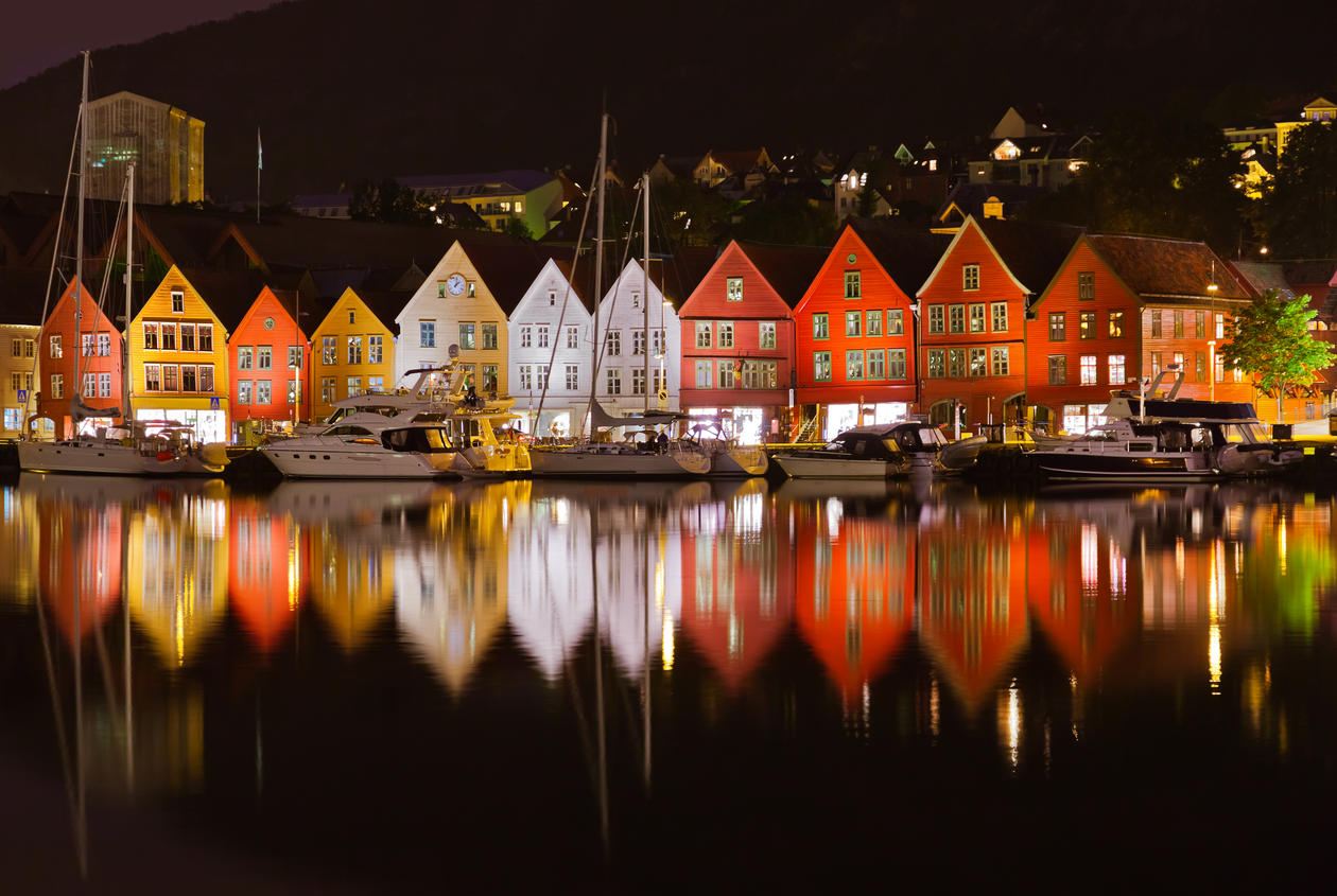 By night, Bryggen with lights on is reflected in the sea.