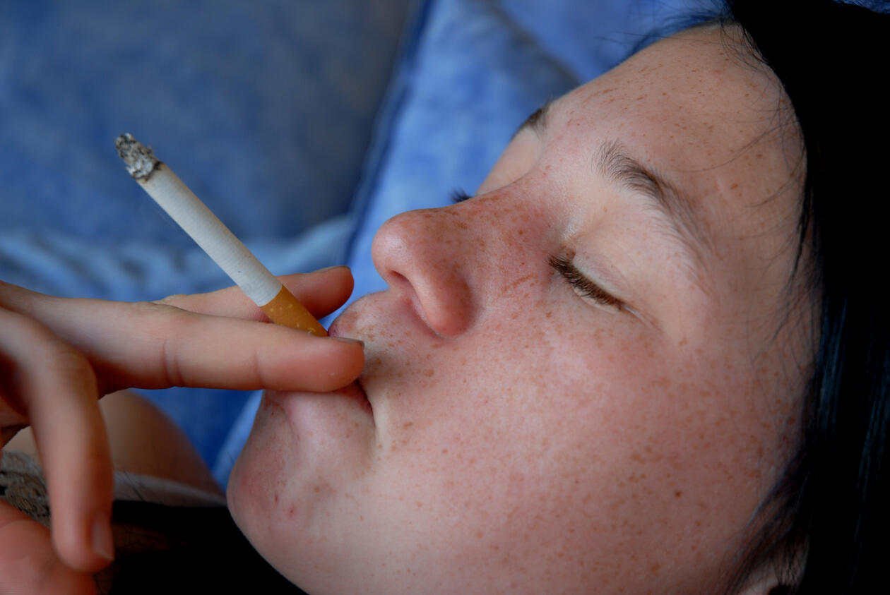 ungdom som røyker - hen ligger på en pute med øynene lukket og har en sigarett mellom fingrene