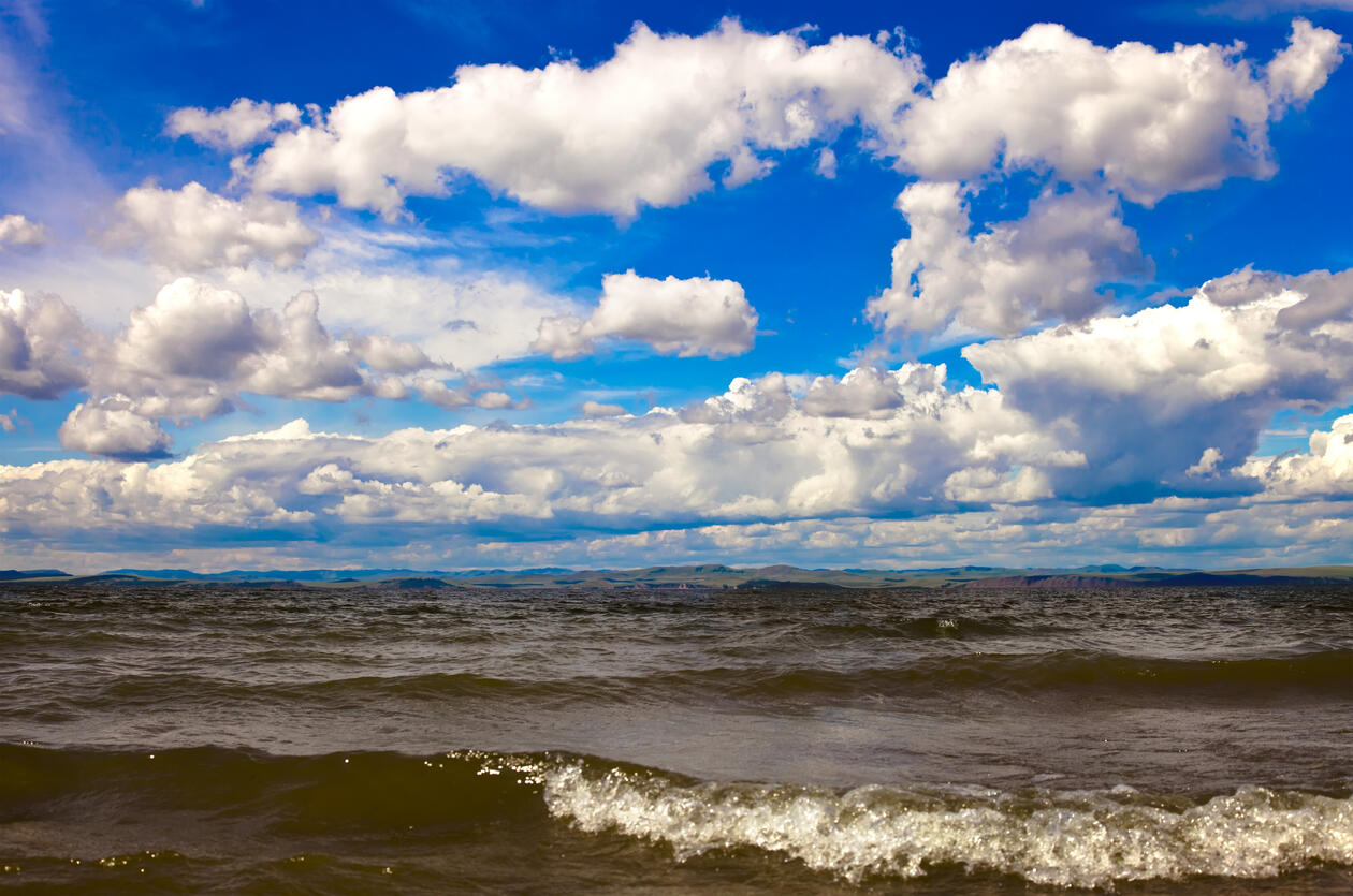 Photo of the ocean with a blue sky with light clouds.