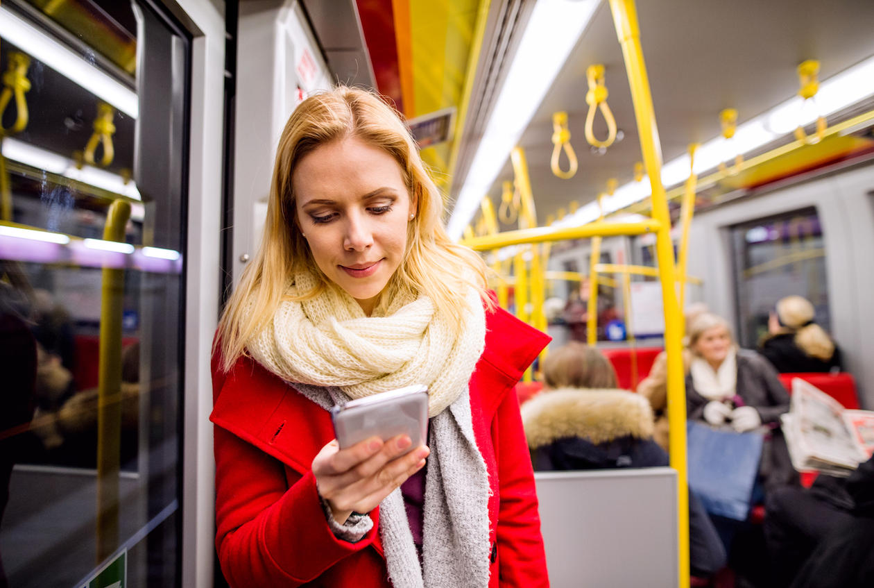 Kvinne leser på mobilen på bussen
