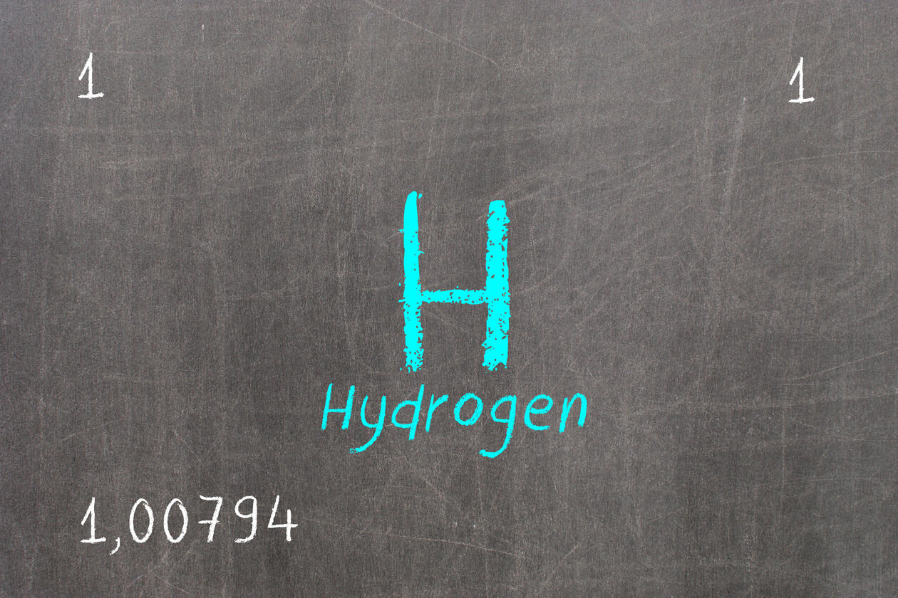 Image of the chemical symbol H representing hydrogen written with white chalk on a green blackboardk on
