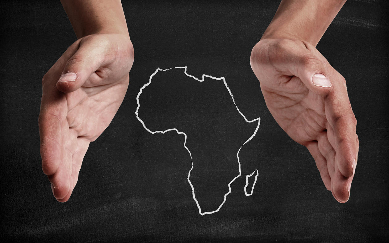 Illustration photo showing two hands cupping an outlined map of the African continent.