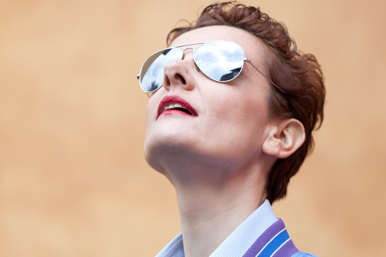 Woman with sunglasses looking up in the sky 