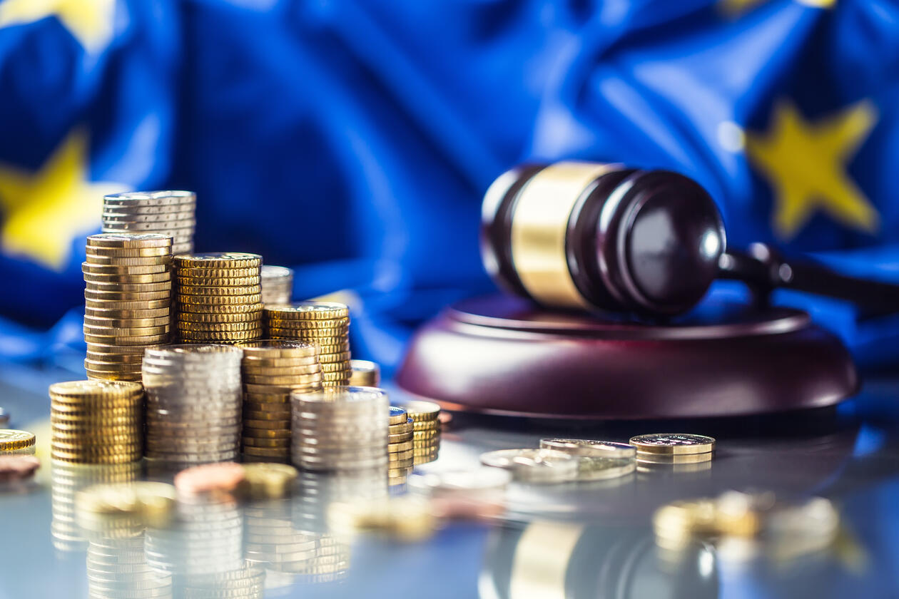 Bilete av ein stabel med pengar og ein dommarhammar med eit EU-flagg som bakgrunn