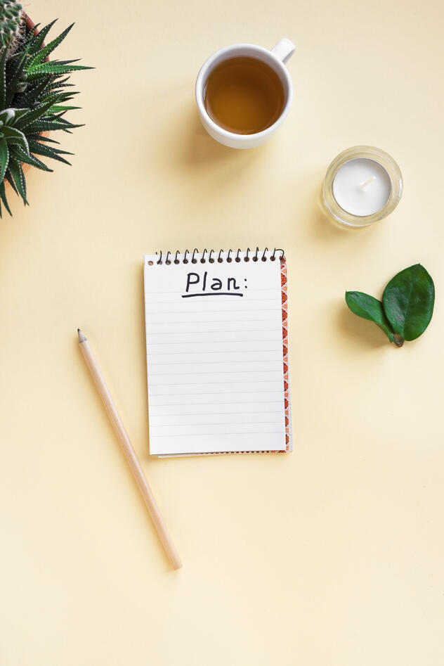 Bilde av notatblokk med ordet "Plan", en blyant, en tekopp og en plante