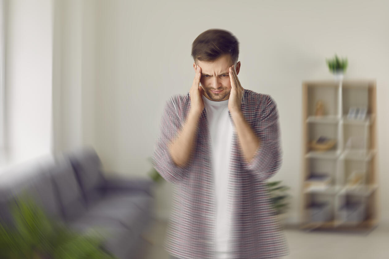 bilde av en ung mann som ar seg til hodet, omgivelsene rundt er tåkete, som å beskrive fornemmelsen i hodet den unge mannen har