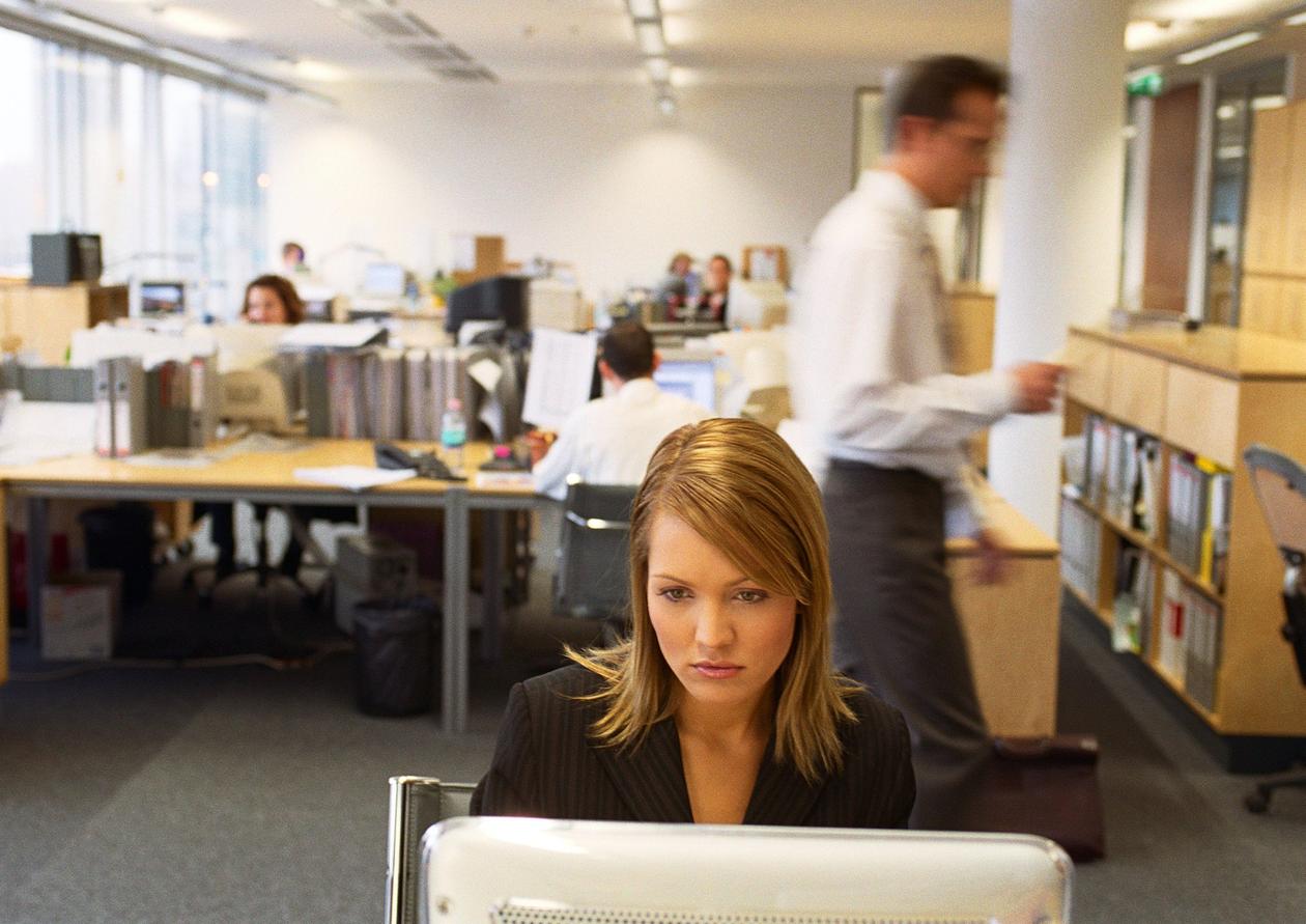 kontorlandskap. kvinne med laptop i forgrunnen