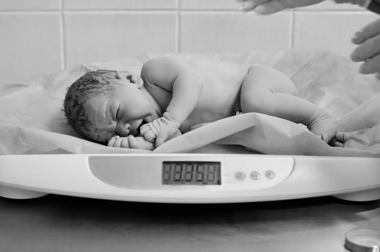 nyfødt baby som gråter og ligger på vekt