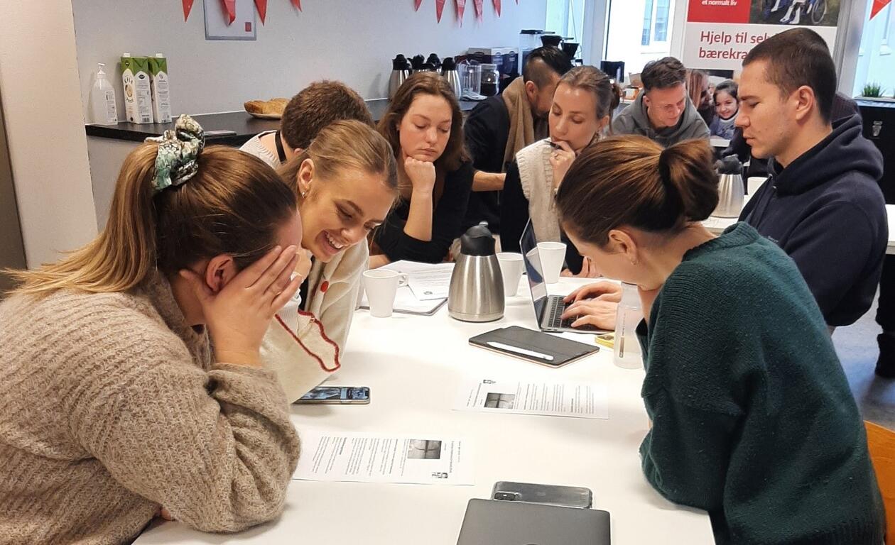Elever på videregående skole sitter rundt et bord og jobber sammen om en oppgave.
