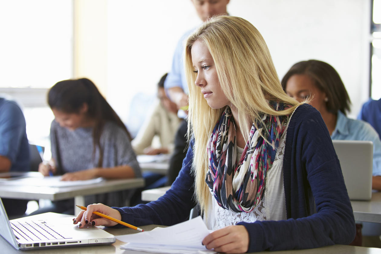 Ung kvinne som avlegger eksamen på laptop i klasserom