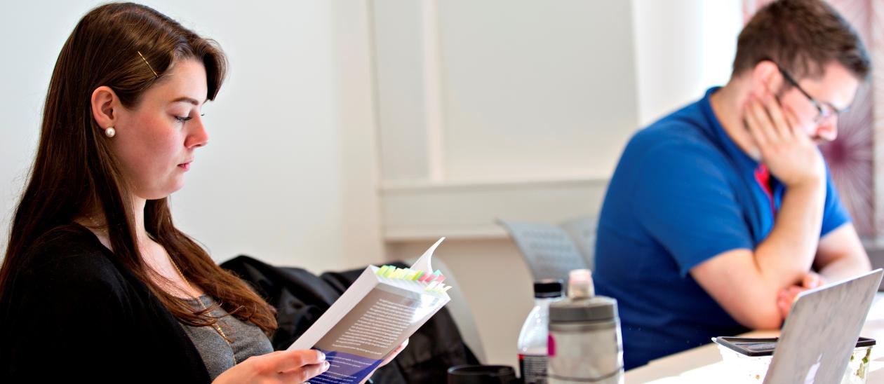 To studenter, jente og gutt sitter og jobber ved et bord.