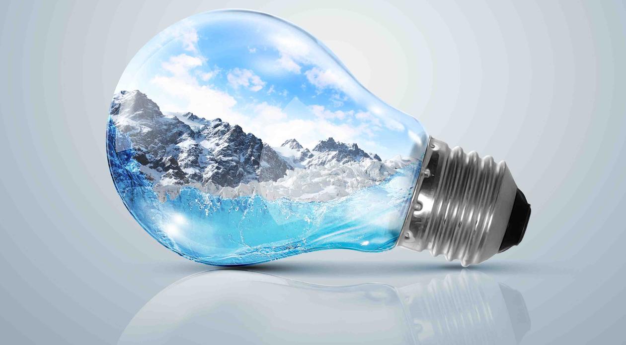 Stock photo image of light bulb with mountain landscape pictured inside the bulb; indicating the link between energy consumption and environmental issues.
