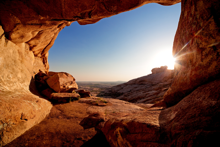 Entrance to cave and the sunset in desert mountains