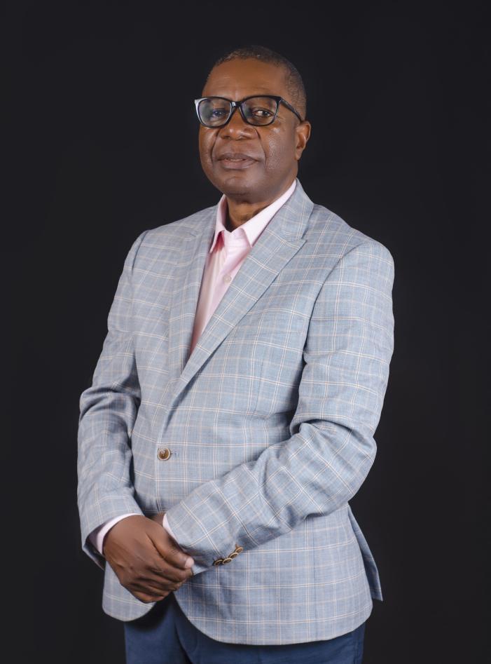 Man posing for camera. Pink shirt and grey jacket