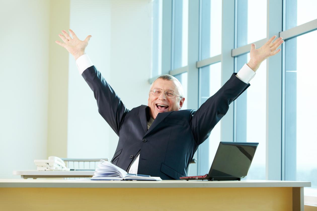 Bilde av glad mann bak skrivebord.