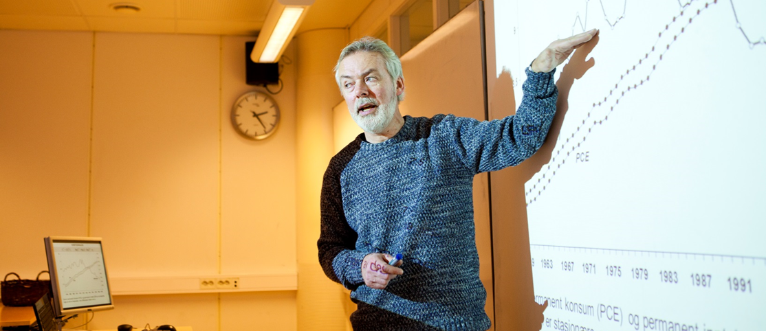 En mann foreleser foran en illustrasjon i et klasserom