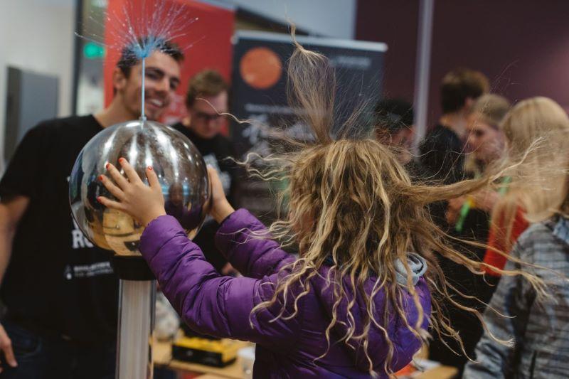 Et barn gjør fysikkeksperiment, holder på en elektrisk kule og håret reiser seg