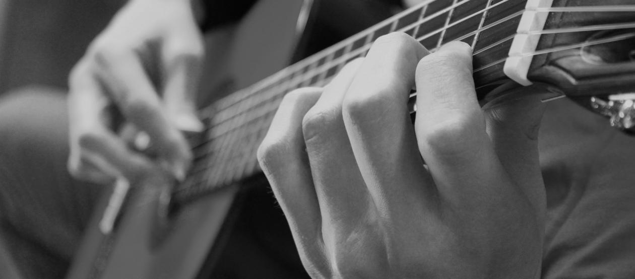 illustrasjonsbilde av en gitarist som spiller gitar. utsnitt kun av gripebrett og begge hendene. 
