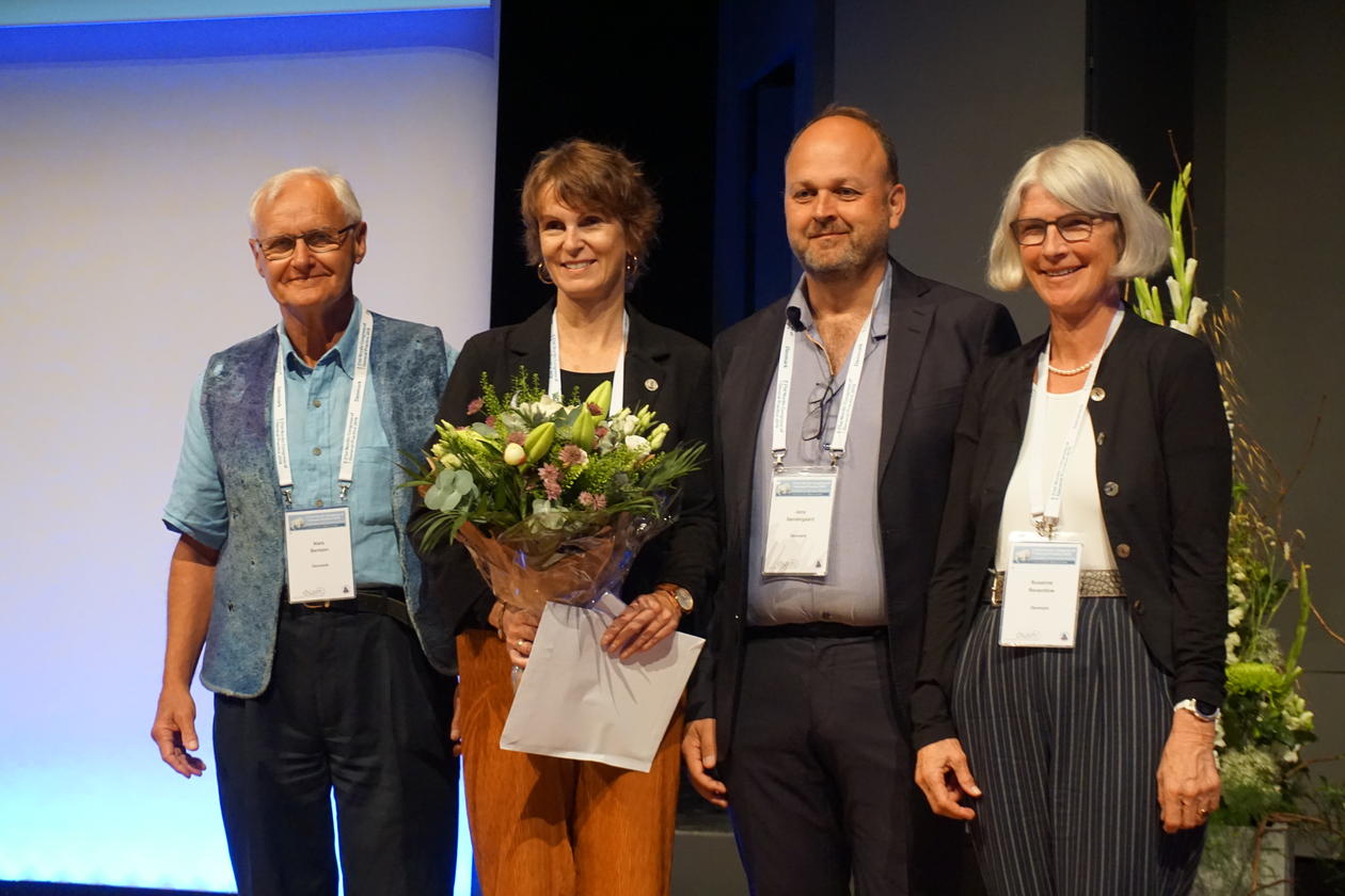 Guri Rørtveit holden en blomst, står sammen med tre andre. Har mottatt en pris