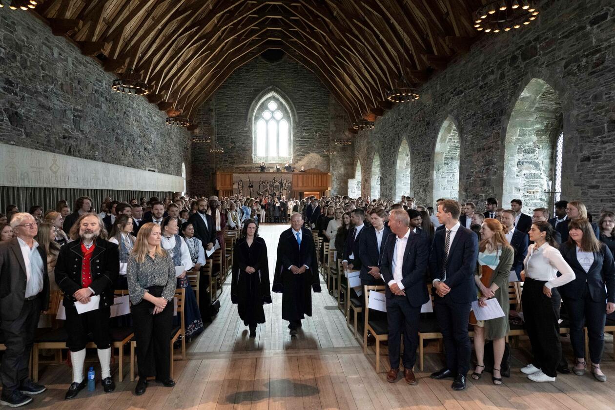 Oversiktsbilde inne i en fullsatt Håkonshall. Prosesjon med dekanatet i forkant. Instituttledere i forkant og bachelorkandidater i salen.