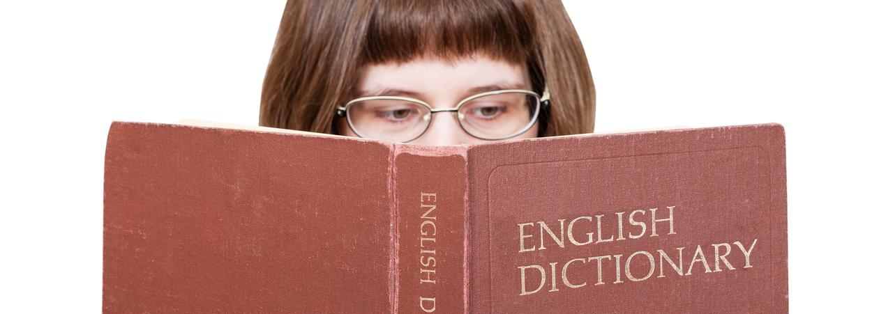 Jente med briller leser i en English dictionary