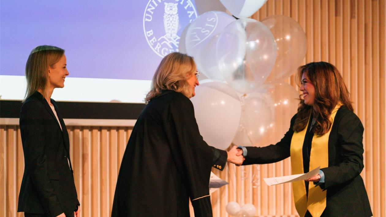 Maria Camila Salazar Patiño gratuleres av dekan Sigrid Schütz og LLM-fagansvrlig Ingrid Barlund