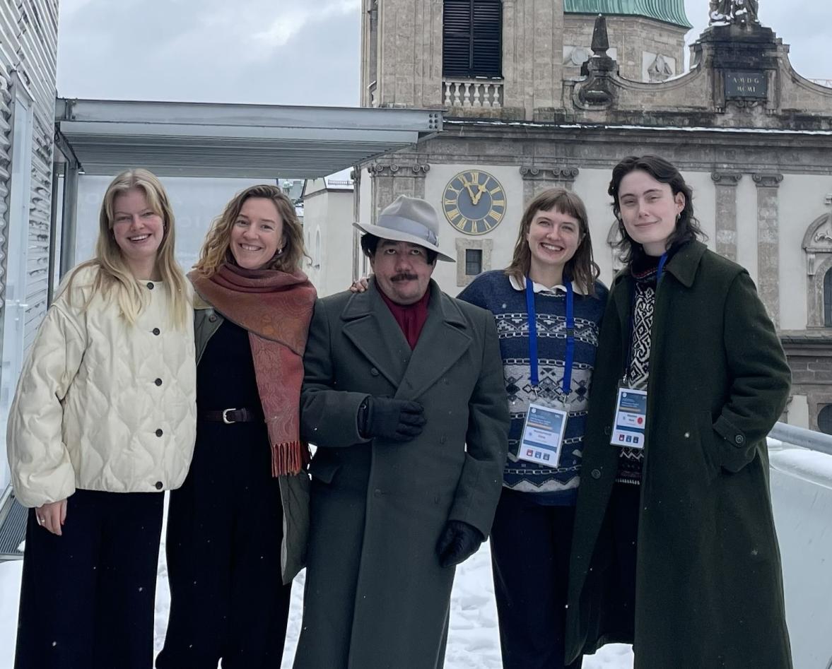 Five people posing in front of a an old building