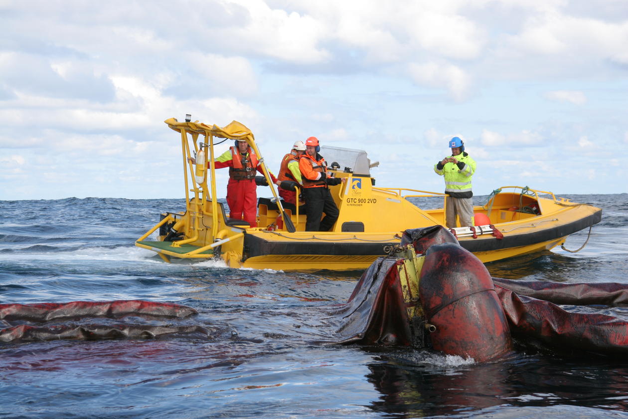Øvelse i oljerydding i Nordsjøen. En liten båt, med fire personer, samt utstyr på havet.