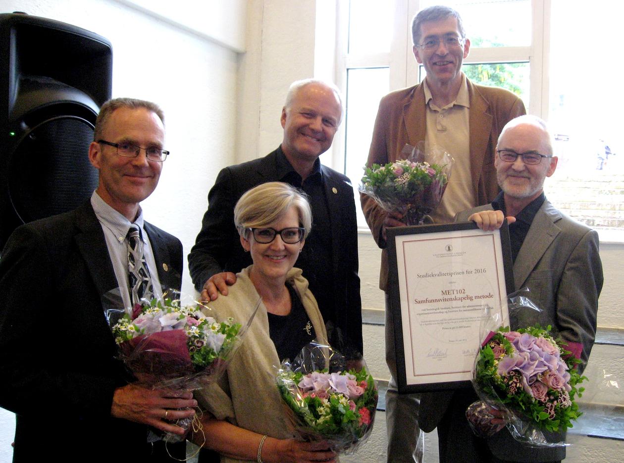 De fire mottakerne av Studiekvalitetsprisen og dekanen smiler mot kamera med blomster og diplom