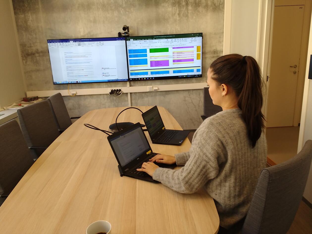 Picture of one person working at computer and screens at DIGSSCORE
