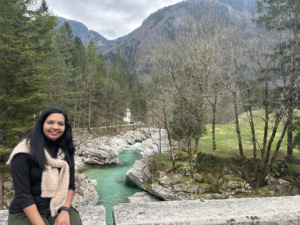 Young woman infront of river with mountains in background